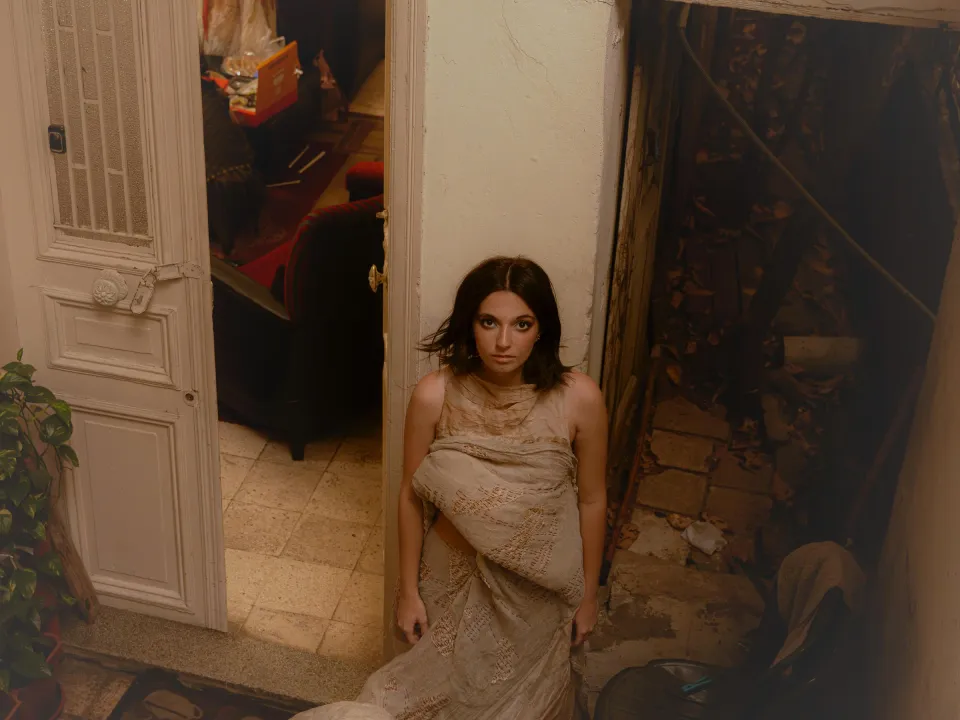 Woman in a draped fabric dress standing in a doorway, seen from above
