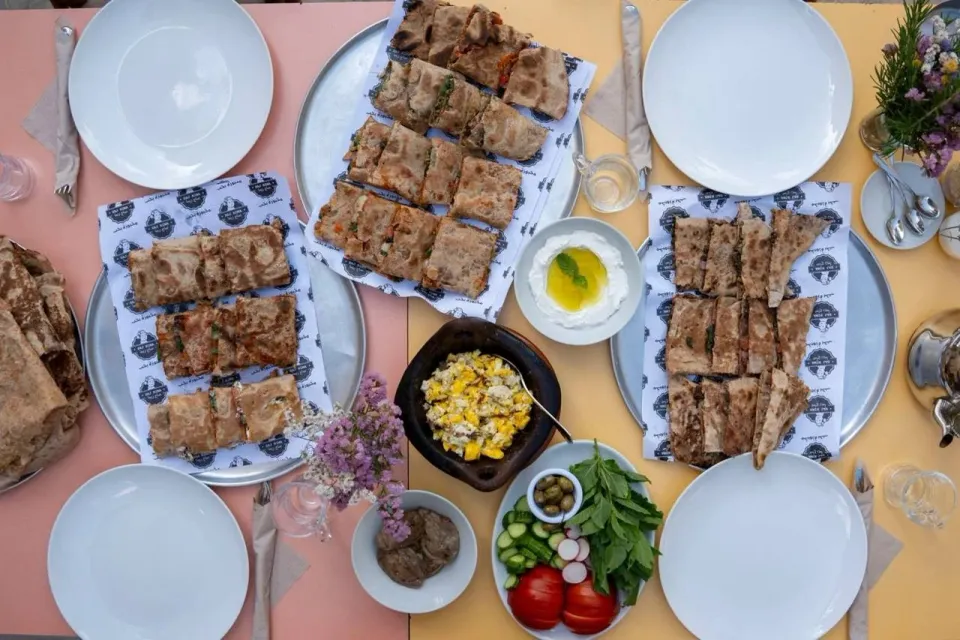 Overhead view of saj flatbreads, labneh and eggs laid out on a table
