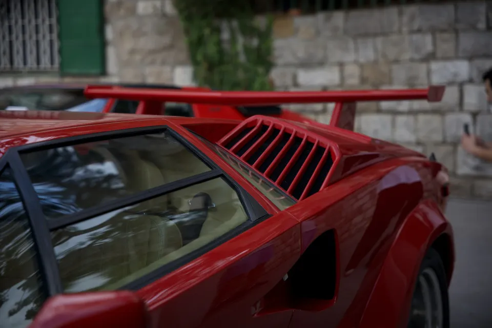 Red Lamborghini Countach with a rear wing parked on a stone street