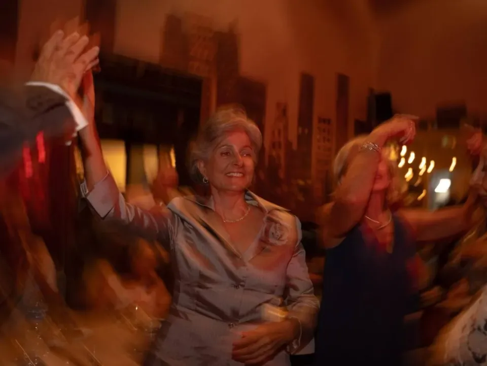 Smiling woman dancing with raised hand at a birthday dinner